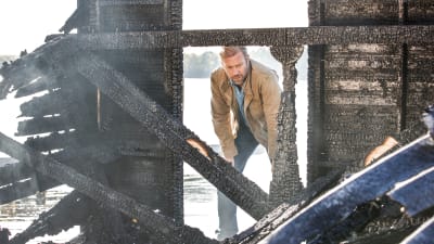 Karaktären Thomas vid en nerbränd byggnad.