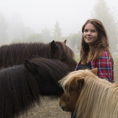 Sabina Granbacka tillsammans med sina tre hästar. Alla hästar står runt henne, med ansiktet mot henne.