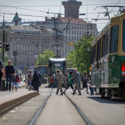 Raitiovaunukiskot ja raitiovaunuja jalankulkijoiden joukossa Helsingissä kesällä.