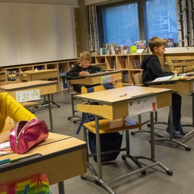 Skolelever i Salo svenska skola sitter vid pulpeten och skriver. 