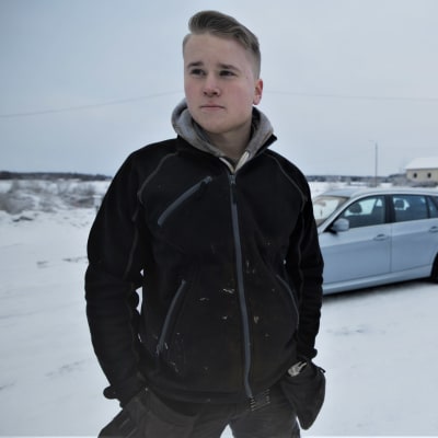 Porträttfoto av Oliver Majors med bil i bakgrunden