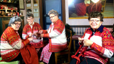 Fyra kvinnor klädda i korsnäströjor arbetar på korsnäströjor.