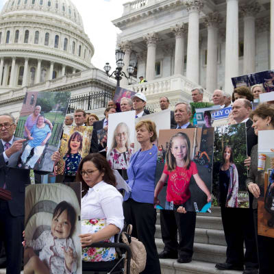 Minoritetsledaren och demokraten Chuck Schumer håller upp bilder på människor som skulle förlora sin sjukvårdsförsäkring republikanernas nya sjukvårdsförsäkring, vid en presskonferens utanför den amerikanska kongressen den 27 juni 2017. 