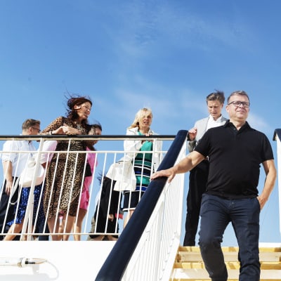 Petteri Orpo och hans partiledning på ett fartyg mot blå himmel