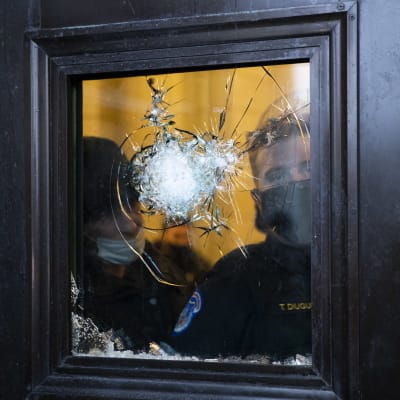Polis tittar ut genom ett krossat fönster.