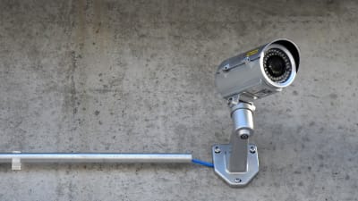 En övervakningskamera monterad på en yttervägg i betong.