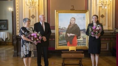 Taiteilija Timo Vuorikoski seisoo vaimonsa kanssa Anna-Kaisa Ikosta esittävän teoksen vieressä. Teoksen oikealla puolella seisoo Anna-Kaisa Ikonen.