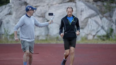 A ultra-run event. Man running and an other man streaming with mobile phone.