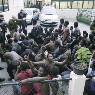 Migranter firar, omgivna av spanska myndigheter, efter att de lyckats ta sig över gränsstängslen till Ceuta 17.2.2017