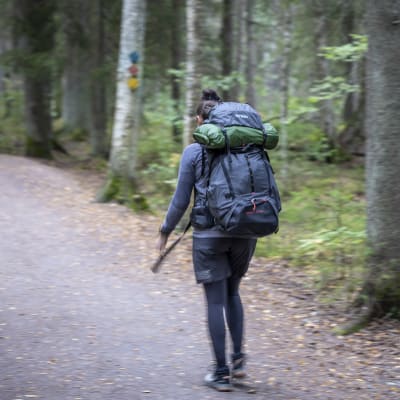 Saara Lehtinen kävelee metsässä rinkka selässä.