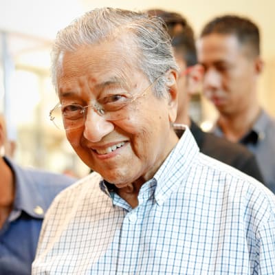 En äldre malaysisk man i rutig skjorta.