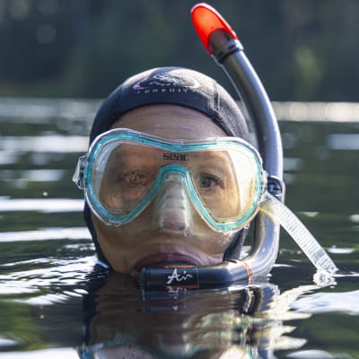 Valokuvaaja Satu Vaarula  seisoo vedessä sukelluslasit ja snorkkeli päässä. 