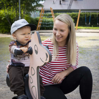 Julius ja Heli Uusitalo leikkimässä leikkipuistossa. Julius ratsastaa jousikeinussa. 