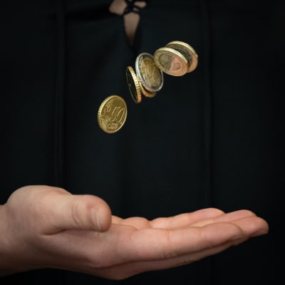 en hand kastar upp mynt i luften mot en svart bakgrund