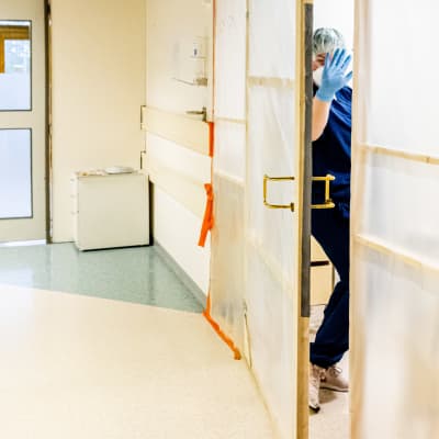 Sairaanhoitaja Essi Laaksosen moikkaa ovenraosta mennessään sulkutilaan ennen koronapotilaiden eristyshuonetta.