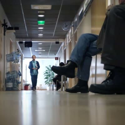 Hoitaja kävelee terveyskeskuksen käytävällä.
