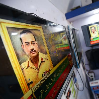 En man i Karachi ser på en tv-skärm med en bild av Pakistans nya arméchef, generallöjtnant Syed Asim Munir.