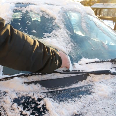 Bilist skrapar rutan på bilen.