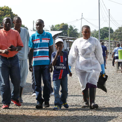 Nathan Gbotoe och hans son Abraham ( i mitten) smittades av ebola men överlevde. Här lämnar de sjukhuset i Liberia i december
