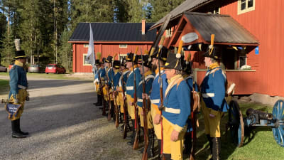 En grupp män står i givakt på en gårdsplan iklädda historiska uniformer