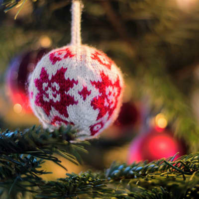 Närbild på en stickad boll i en julgran. 