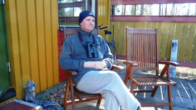Magnus Östman, chefredaktör för Finlands natur, sitter på sin terrass och kikar på fåglar