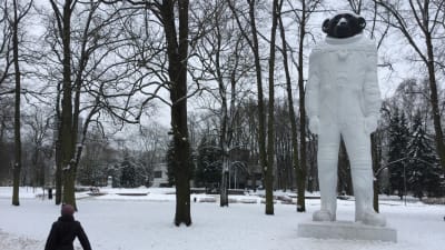 Isskulptur av apa klädd i austronautdräkt i en vintrig park i Rigas centrum