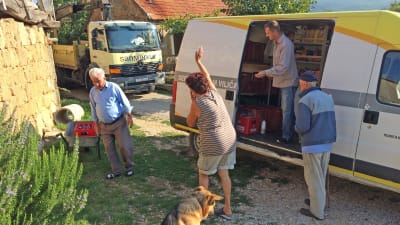 Fyra människor vid en paketbil som kör matvaror till en liten kroatisk by.