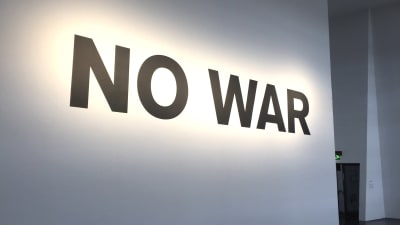 Vit vägg med text där det står No war med stora bokstäver. 