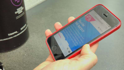 En hand som håller i en telefon där ARS17-mobilguiden syns på displayen.