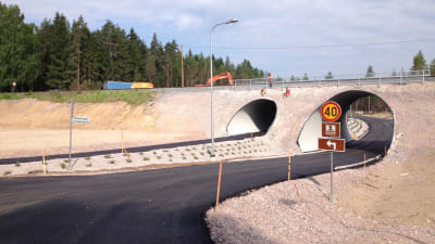 En nybyggd järnvägsundergång för bilar och lätt trafik i Svedja i Karis. Också män i arbetskläder syns på bilden.