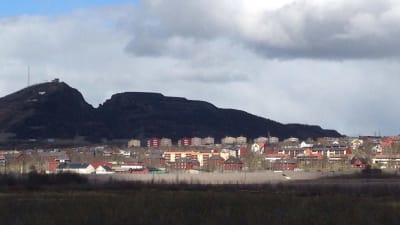 Kiruna med röda och gula hus i förgrunden och den svarta gruvan i bakgrunden.