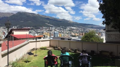 Utsikt från taket på en skola i Ecuador. I bakgrunden reser sig berg mot en blå himmel.