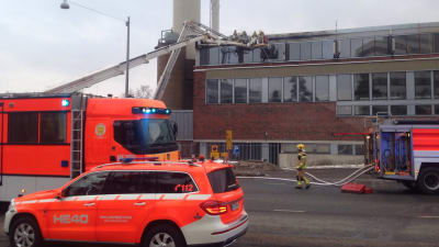 Uttryckningsfordon står parkerade utanför Mejlans sjukhus i Helsingfors. Brandmän jobbar med att släcka branden.