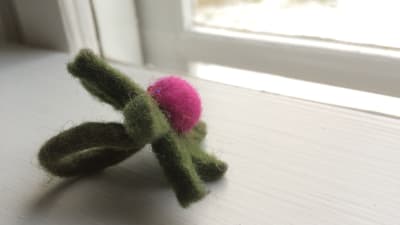 En grön tovad ring med en lila boll