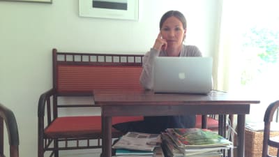 Julia Korkman sitter vid ett bord med en dator framför sig
