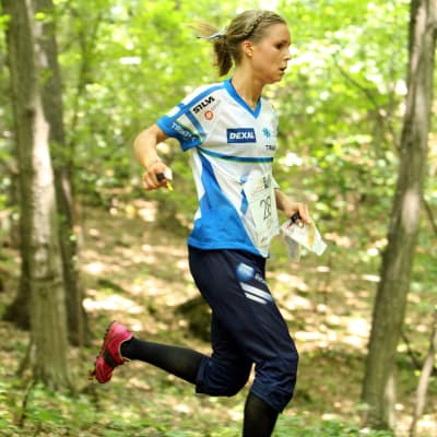 Orienteraren Kirsi Nurmi springer i lövskog.