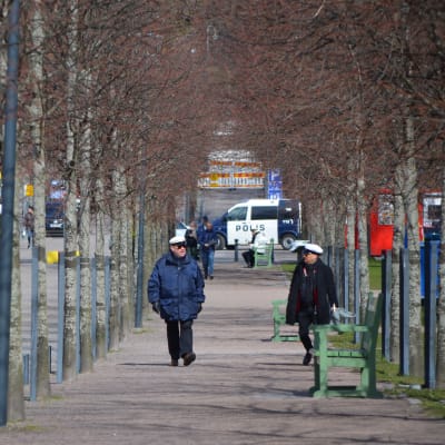 Första maj-firande i Brunnsparken i Helsingfors år 2020. Personer promenerar längs Stora allén.