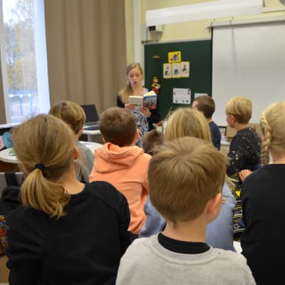 Törnävän koulun tokaluokkalaiset kuuntelevat, kun luokanopettaja Kirsi Jouppila lukee. Lukuagentti Anu Koskela on kuvassa oikealla.