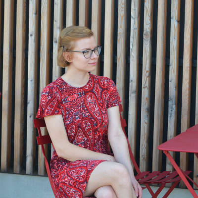 Sofia Wahlroos sitter på en röd bänk. 