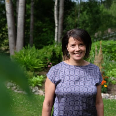 Hanne Aho står i sin trädgård.