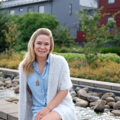 En kvinna sitter framför en rabatt.