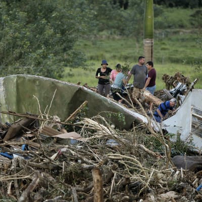 Kuvassa ihmisiä, jotka etsivät uhreja myrskyn tuhoalueella romun keskeltä. 