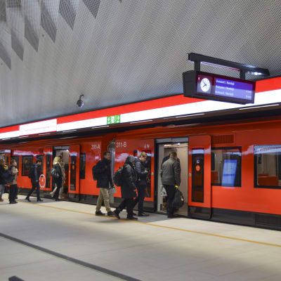 passagerare går in i ett tåg på mattby metrostation på måndag morgon