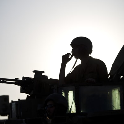 Silhouett av en israelisk soldat som sticker upp ur en stridsvagn.