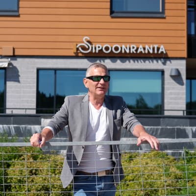 Ben Fuchs står bakom ett metallstaket framför Sibbostrand.