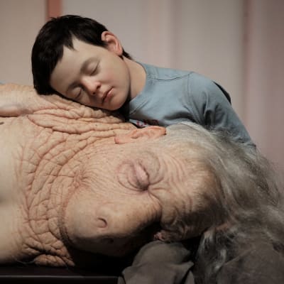Konstverk: en far/morförälder sover i sitt barnbarns famn.