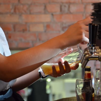 Barpersonal häller upp öl i ett glas från en ölkran.