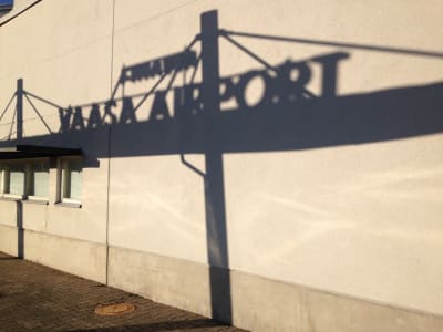 Skuggbild vid Vasa flygplats, i fotot ser man skuggan av flygplatsskylten mot terminalväggen.