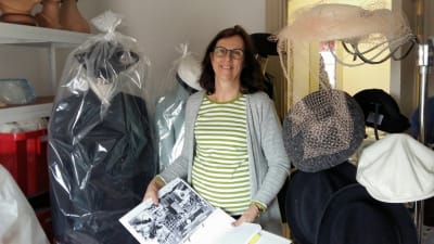 Textilforskare Helena Sandström-Snickars på Österbottens museum planerar en sommarutställning med Elin Nelins hatt, studentmössa och dräkter. På bilden i Helenas händer syns Elin iklädd en av dräkterna och studentmössan i samband med en klassträff.